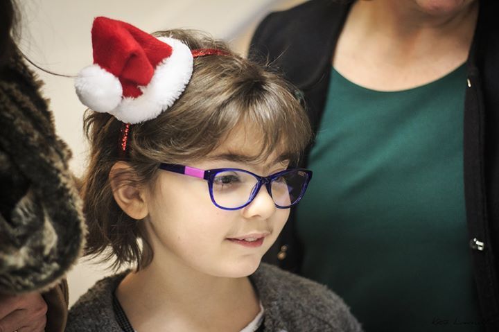 Una bambina che indossa gli occhiali e un cappello da Babbo Natale in testa.