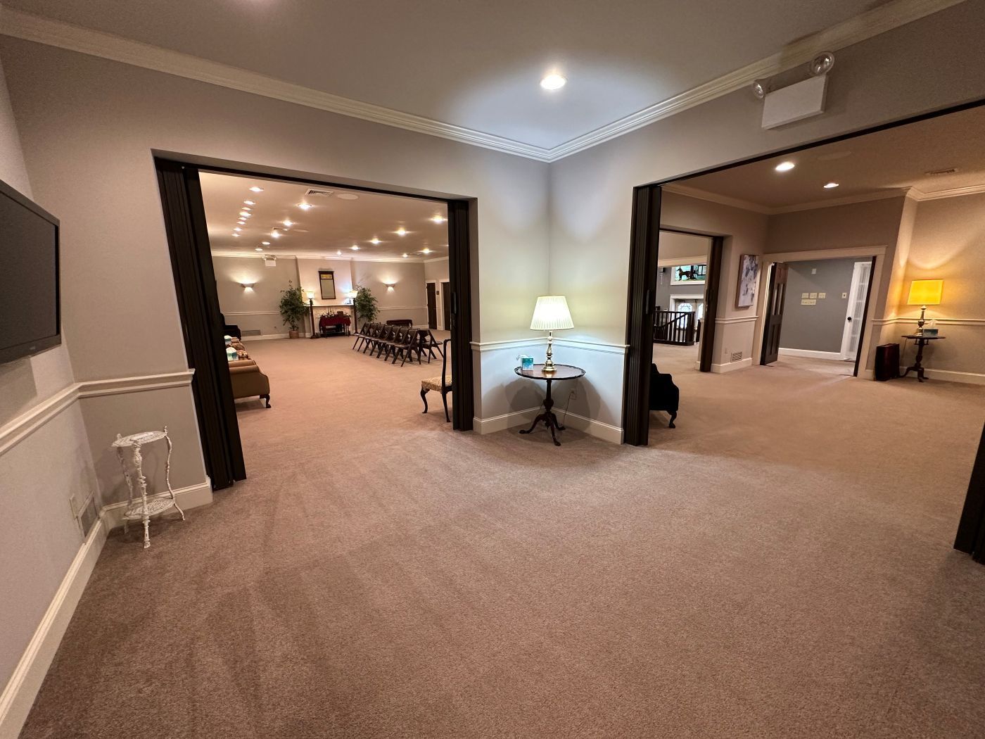 A large room with a carpeted floor and a television on the wall.