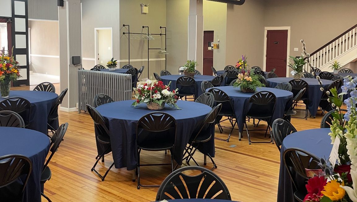 A large room with tables and chairs set up for a party.