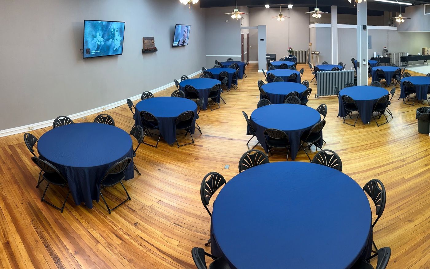A large room filled with tables and chairs with blue tables and blue linens.
