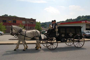 A man is riding in a horse drawn carriage down a street.