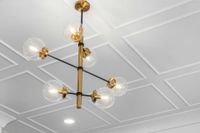 Modern gold chandelier with clear glass globes hanging from a white coffered ceiling