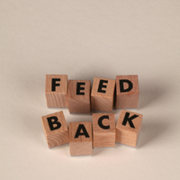 Wooden letter blocks spelling “FEED BACK” on a light background