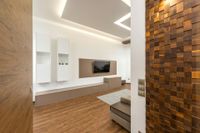 Modern minimalist living room with wood panel wall, white TV unit, and warm wood flooring