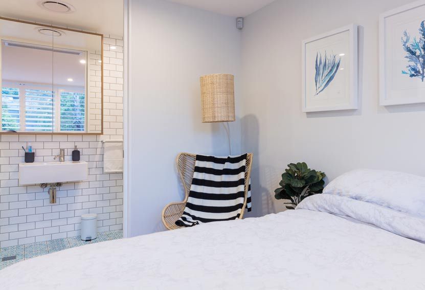 Bedroom With Bathroom. White Bed, Chair With Blanket — Burmah Constructions In Kangaroo Valley, NSW