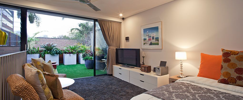 A Modern Bedroom With a Sliding Glass Door Open to a Small Lawn With Plants — Burmah Constructions In Kangaroo Valley, NSW