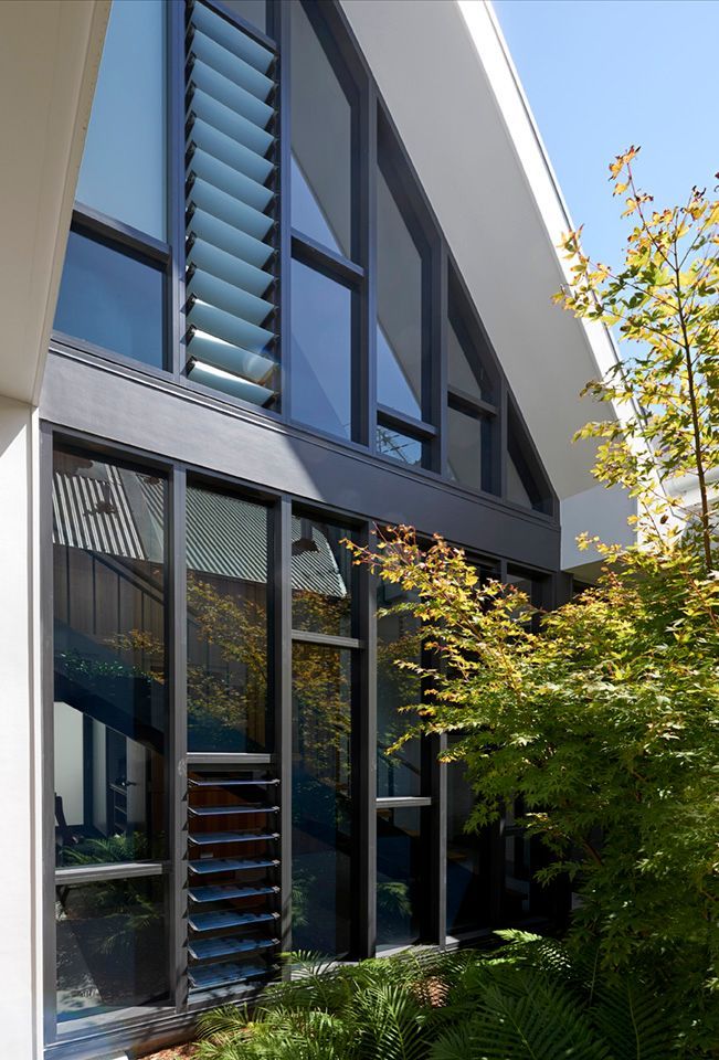 Modern architectural house exterior with large triangular windows, dark frames, and integrated louvered ventilation — Burmah Constructions In Kangaroo Valley, NSW