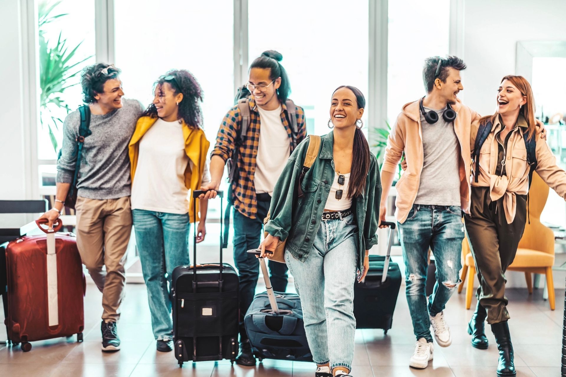 Un gruppo di giovani sta camminando in un aeroporto con i loro bagagli.