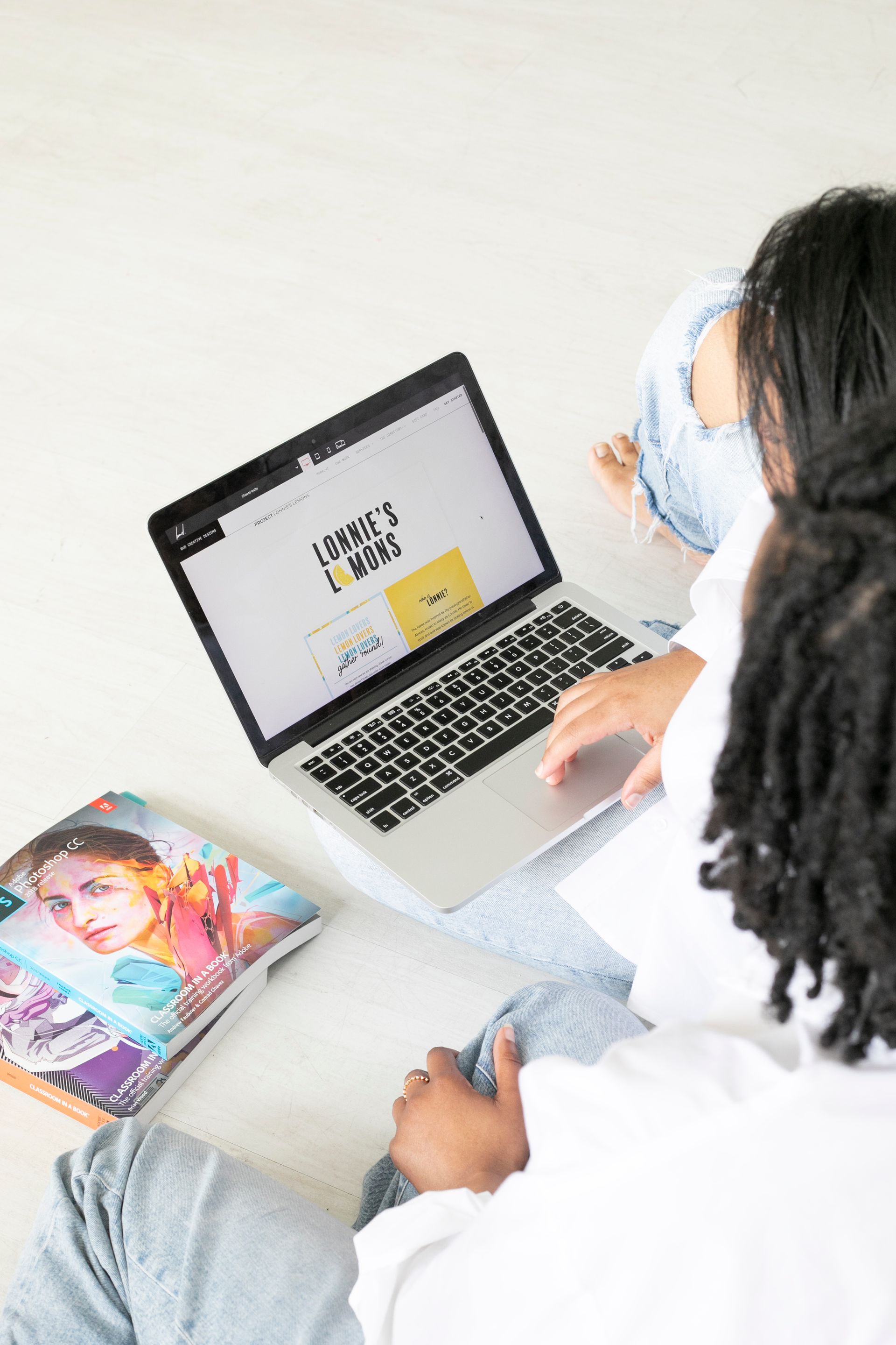 Abria and Joi looking at a laptop displaying branding for Lonnie's Lemons