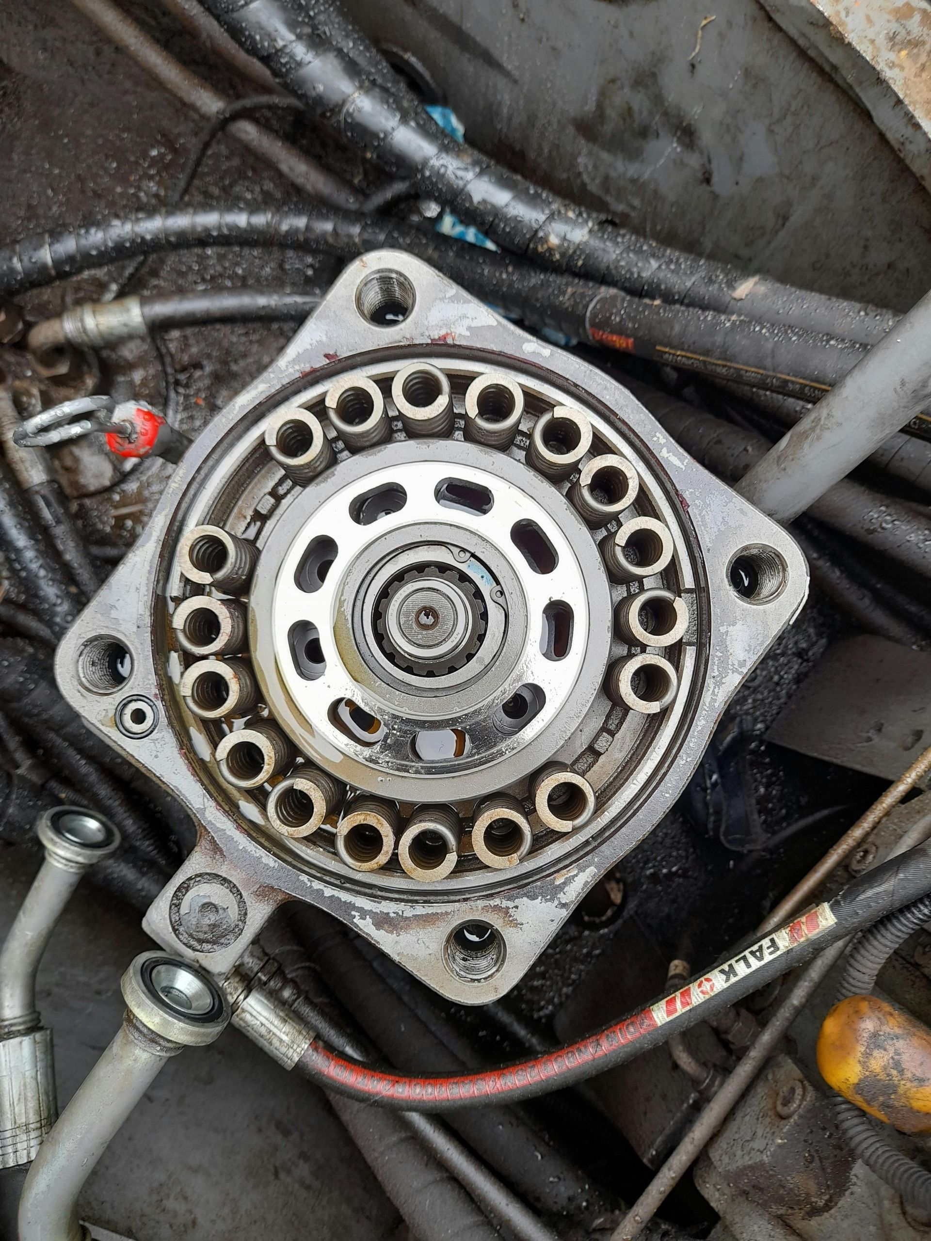 Top-down view of a hydraulic motor with exposed internal components, surrounded by tubes and hoses.
