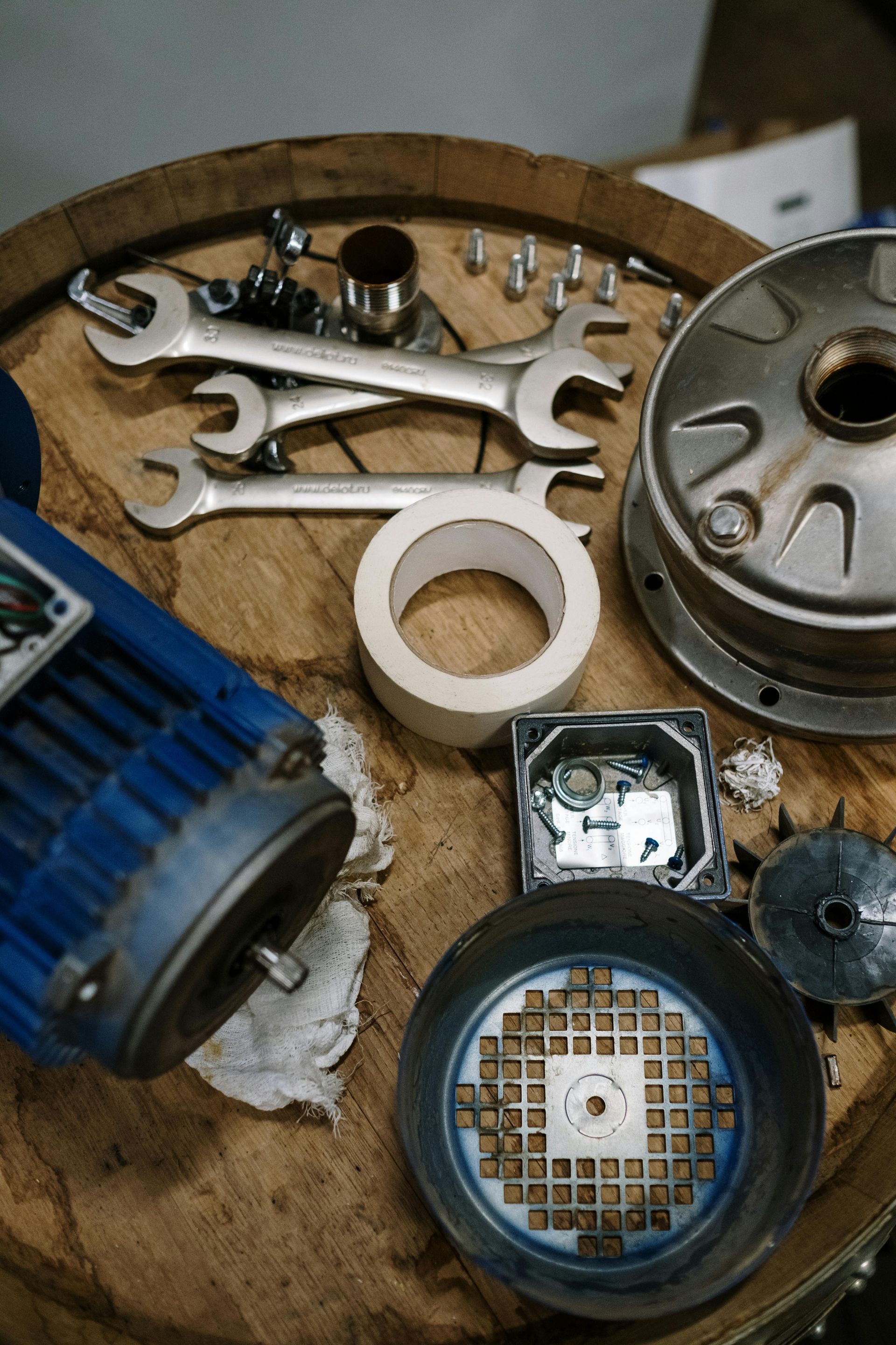 Disassembled blue motor with tools and parts on a wooden surface.