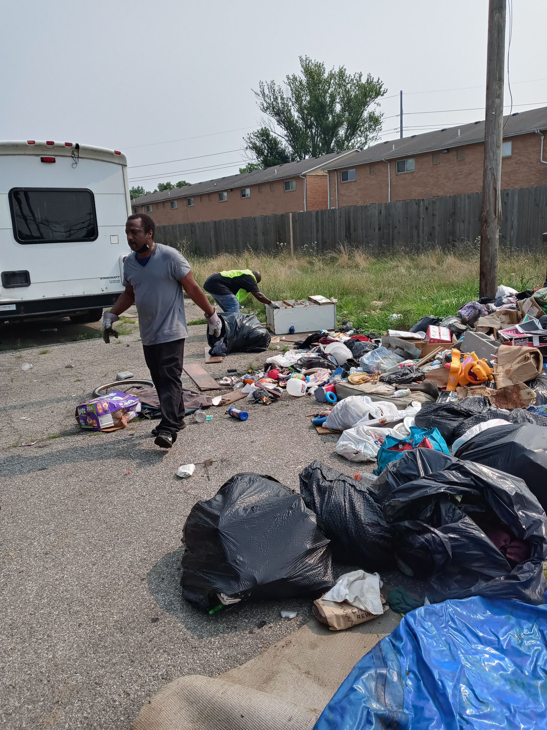 A man is standing in front of a pile of trash.