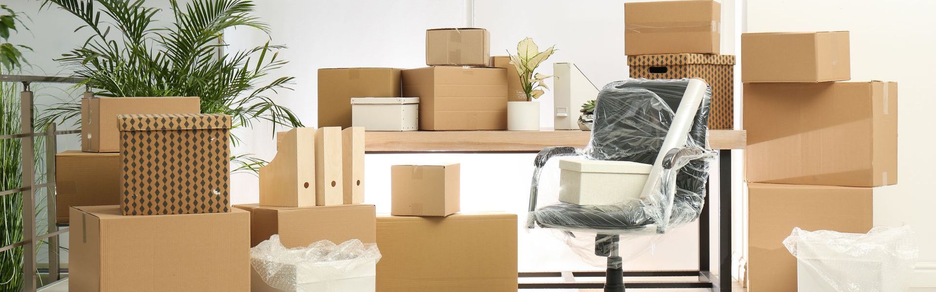 A room filled with lots of cardboard boxes and a chair.