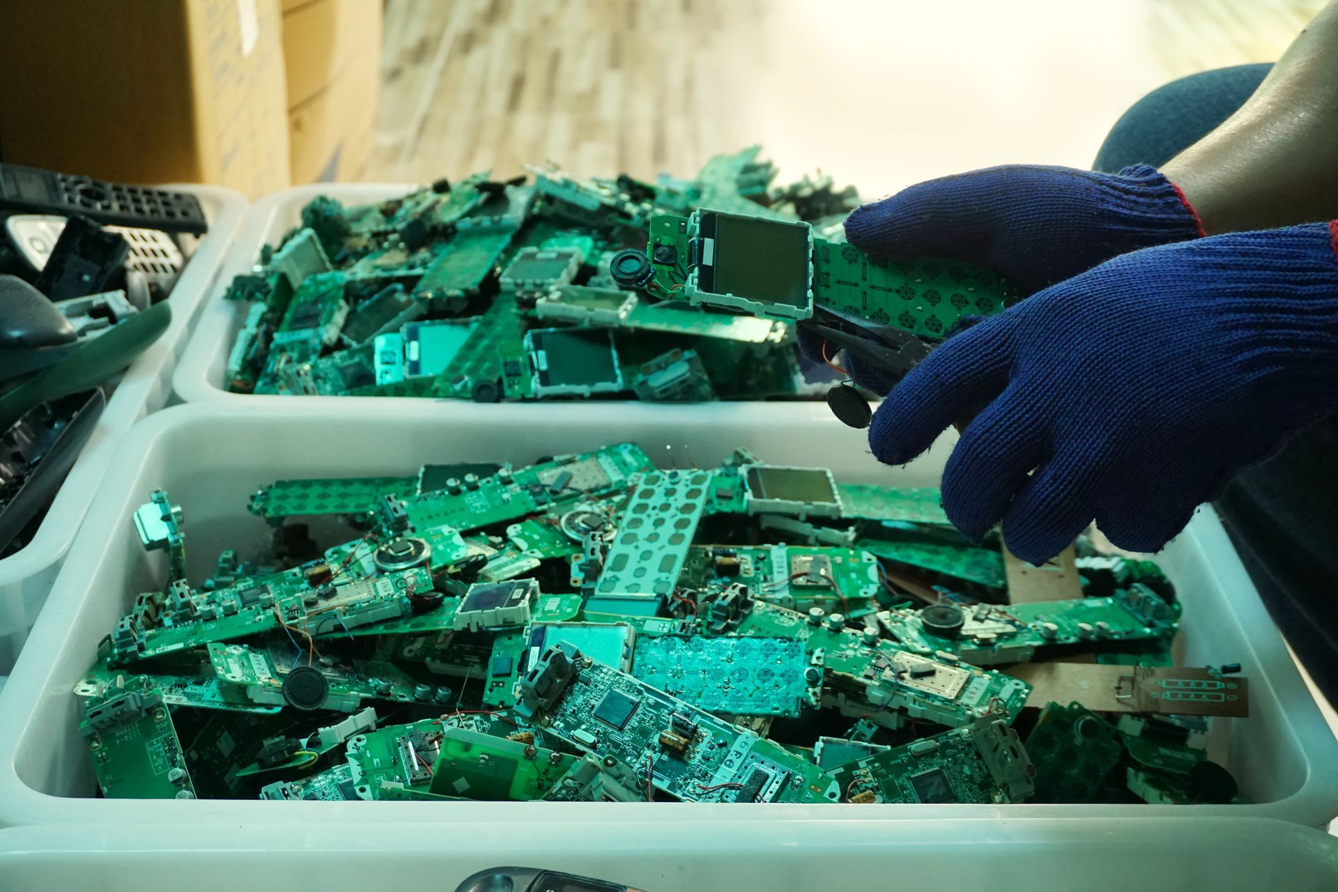 A person wearing blue gloves is holding a motherboard in their hands.