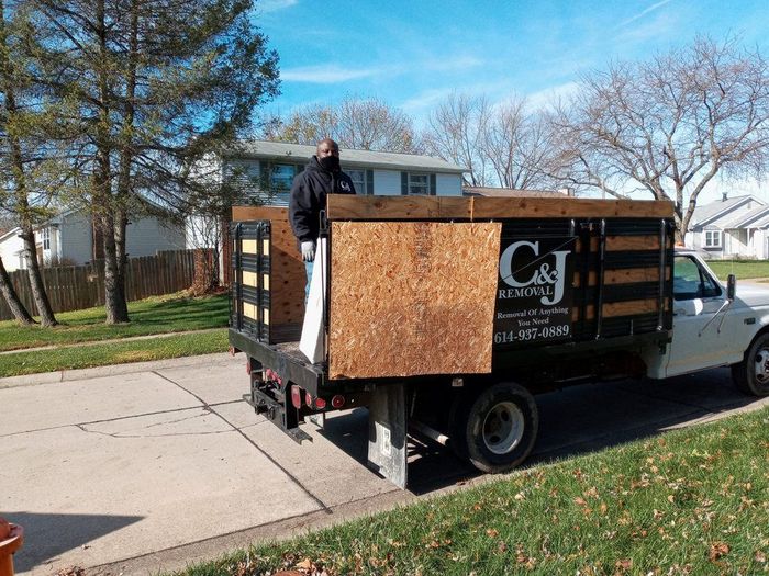 A man is standing on the back of a truck.