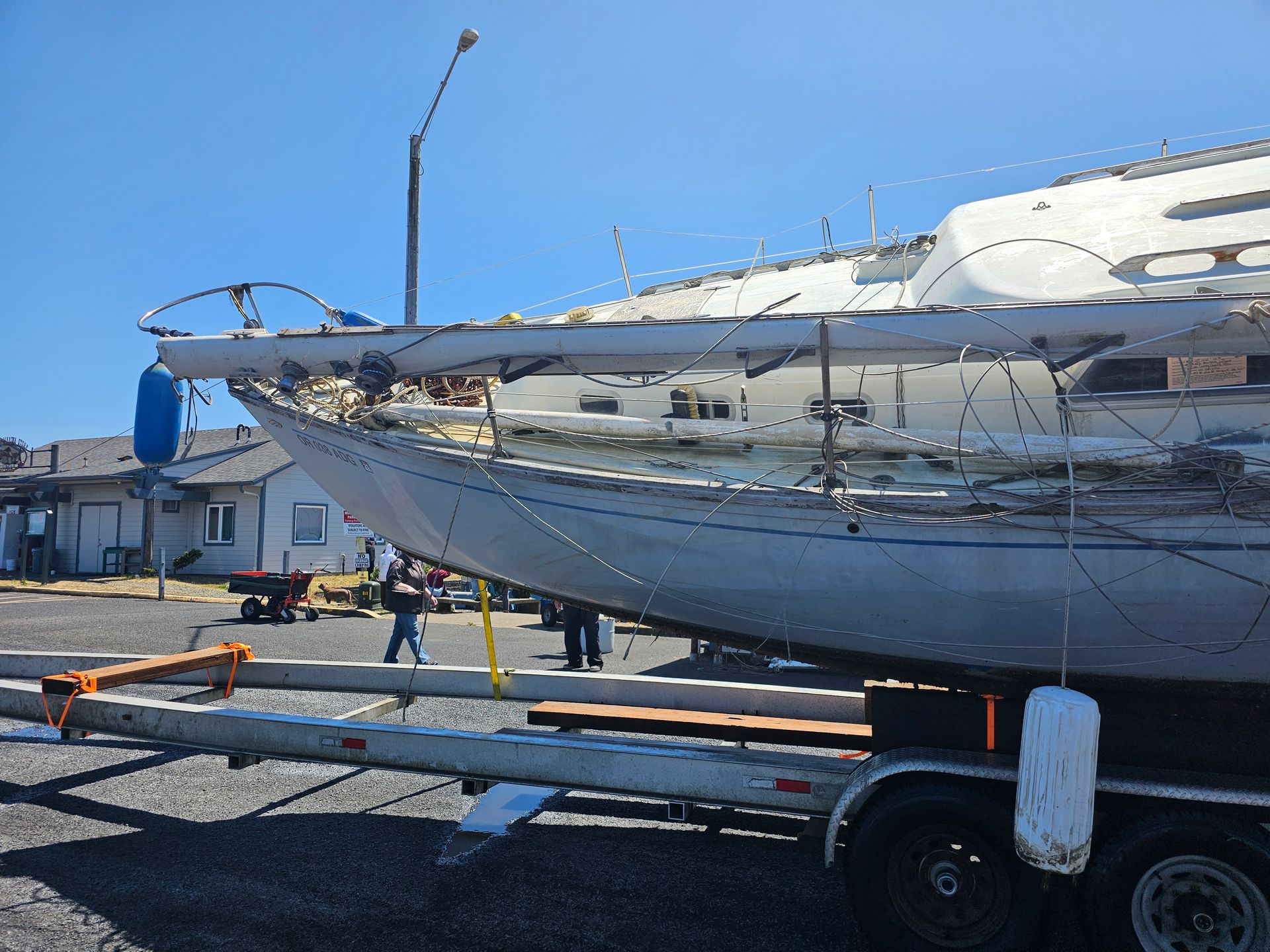 Sailboat on a trailer, being worked on outdoors on a sunny day.