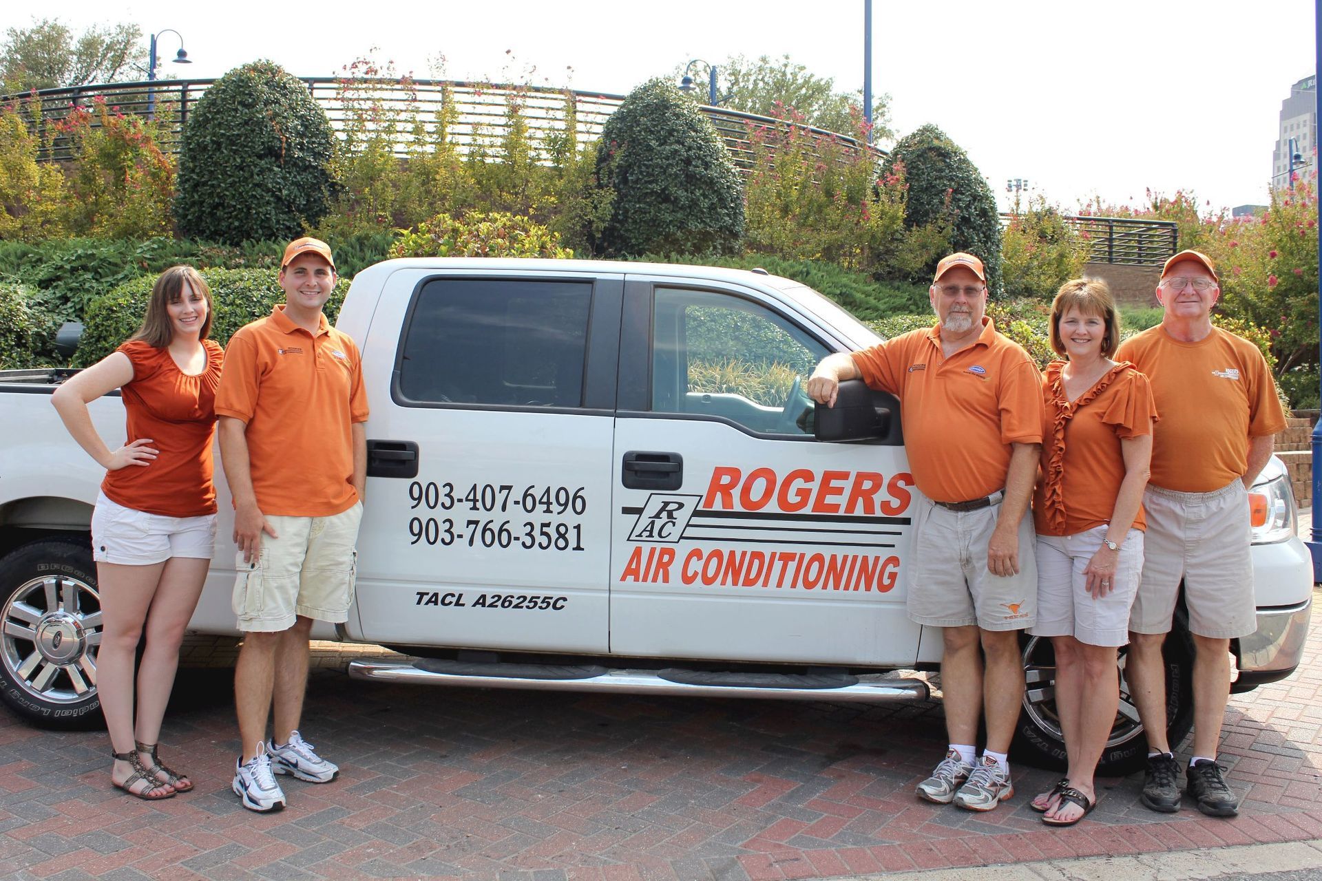 A group of people standing in front of a rogers air conditioning truck