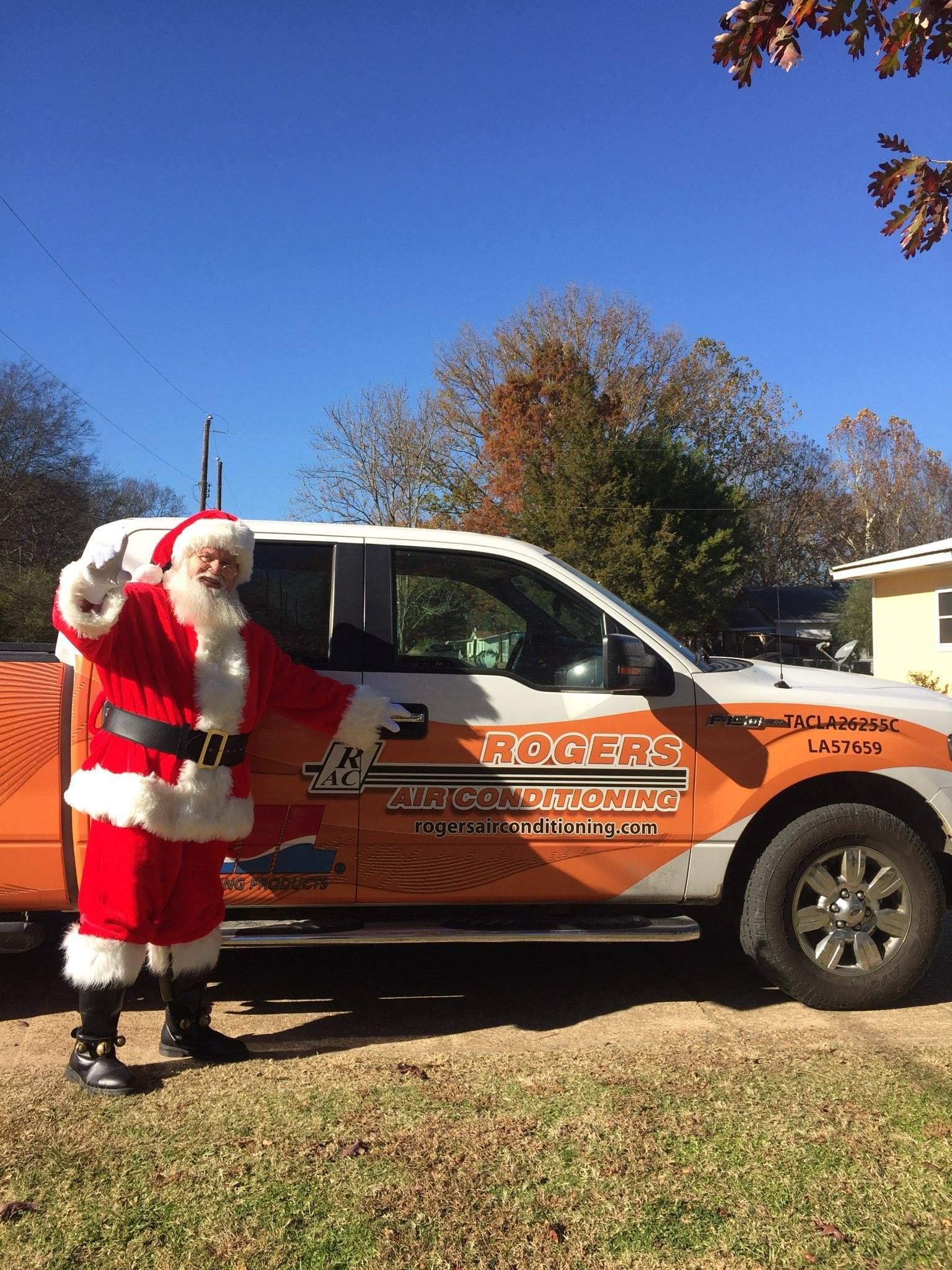 A man dressed as santa claus is standing in front of a truck.