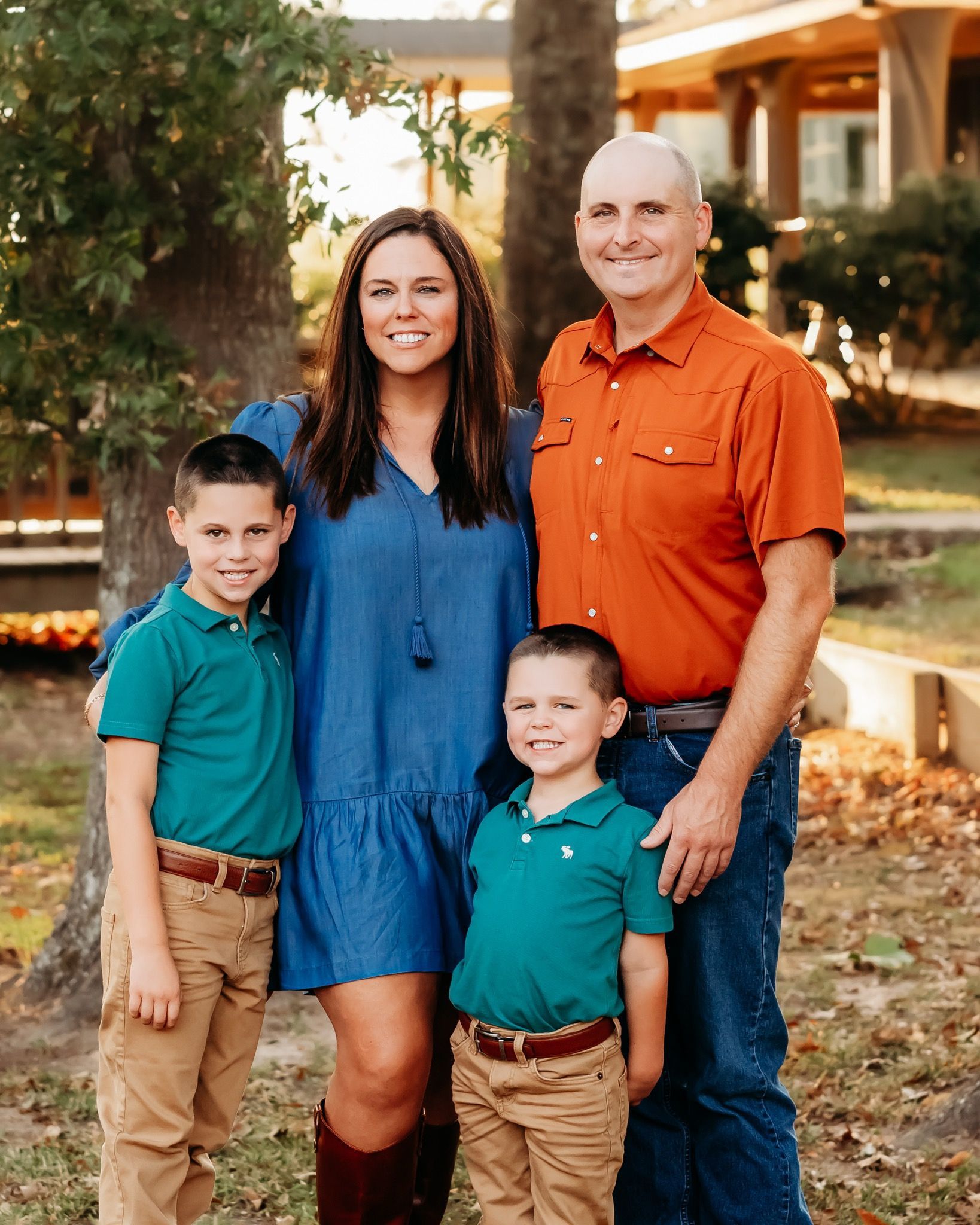 A family is posing for a picture in front of a house.