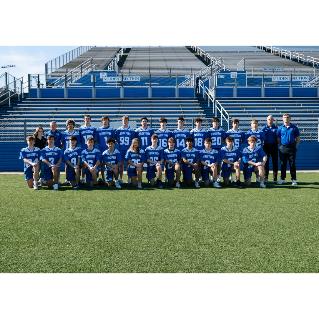 Youth soccer team in blue uniforms posing on a field with bleachers in the background