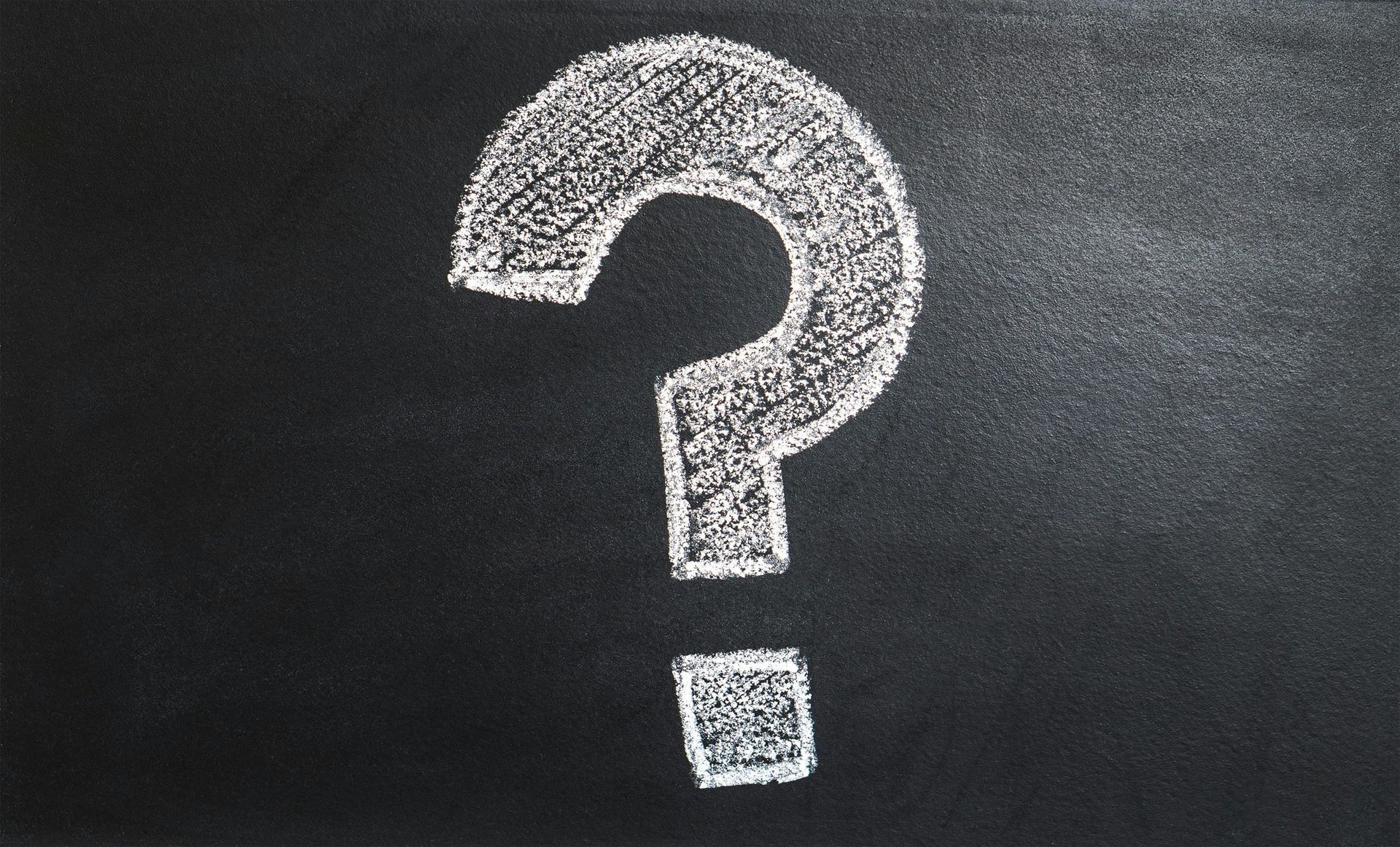 White chalk question mark on a dark chalkboard background.