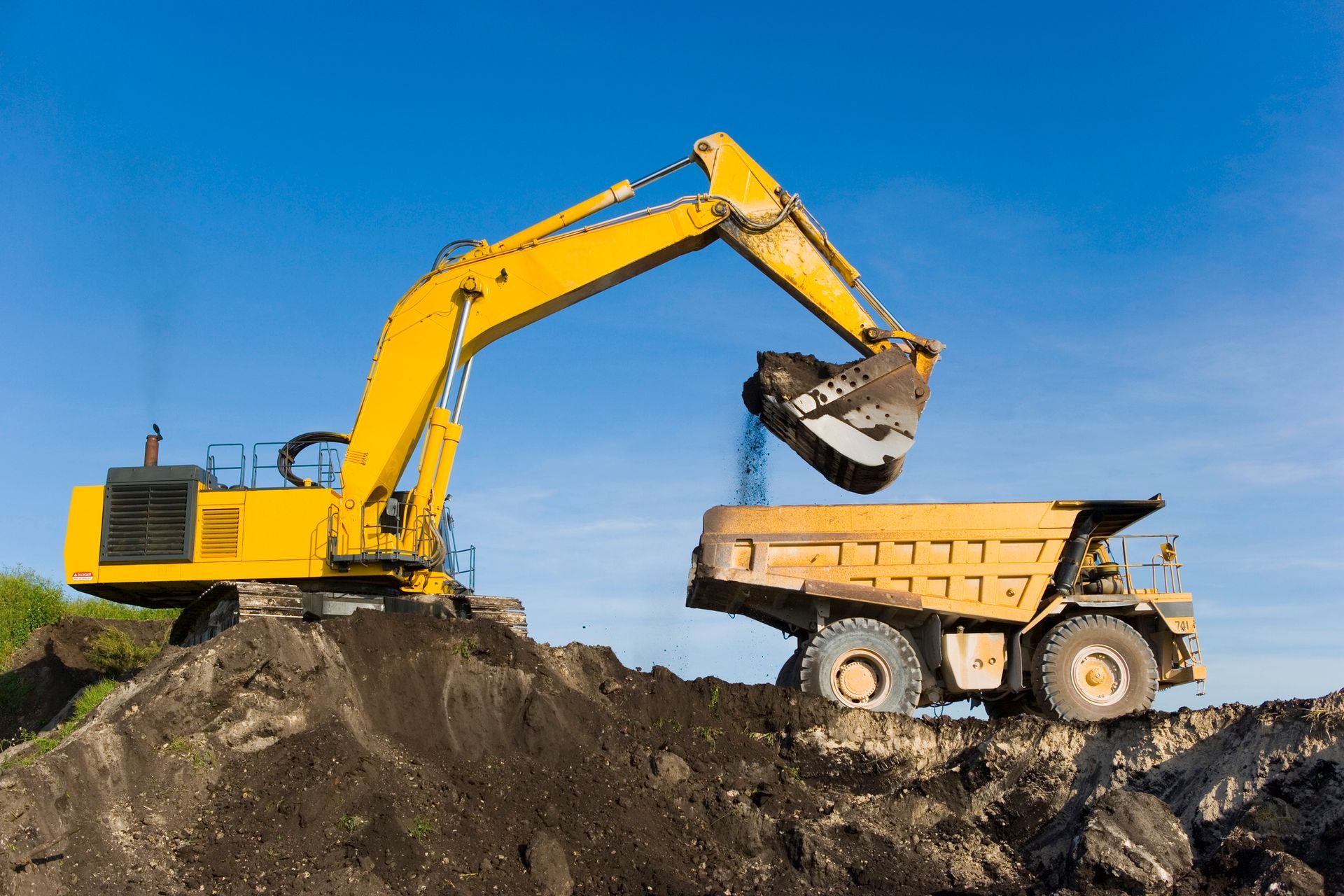 Yellow Excavator Loading Dirt Into a Dump Truck — Madisonville, KY — Wil-Mar Hydraulics & Machine Inc.