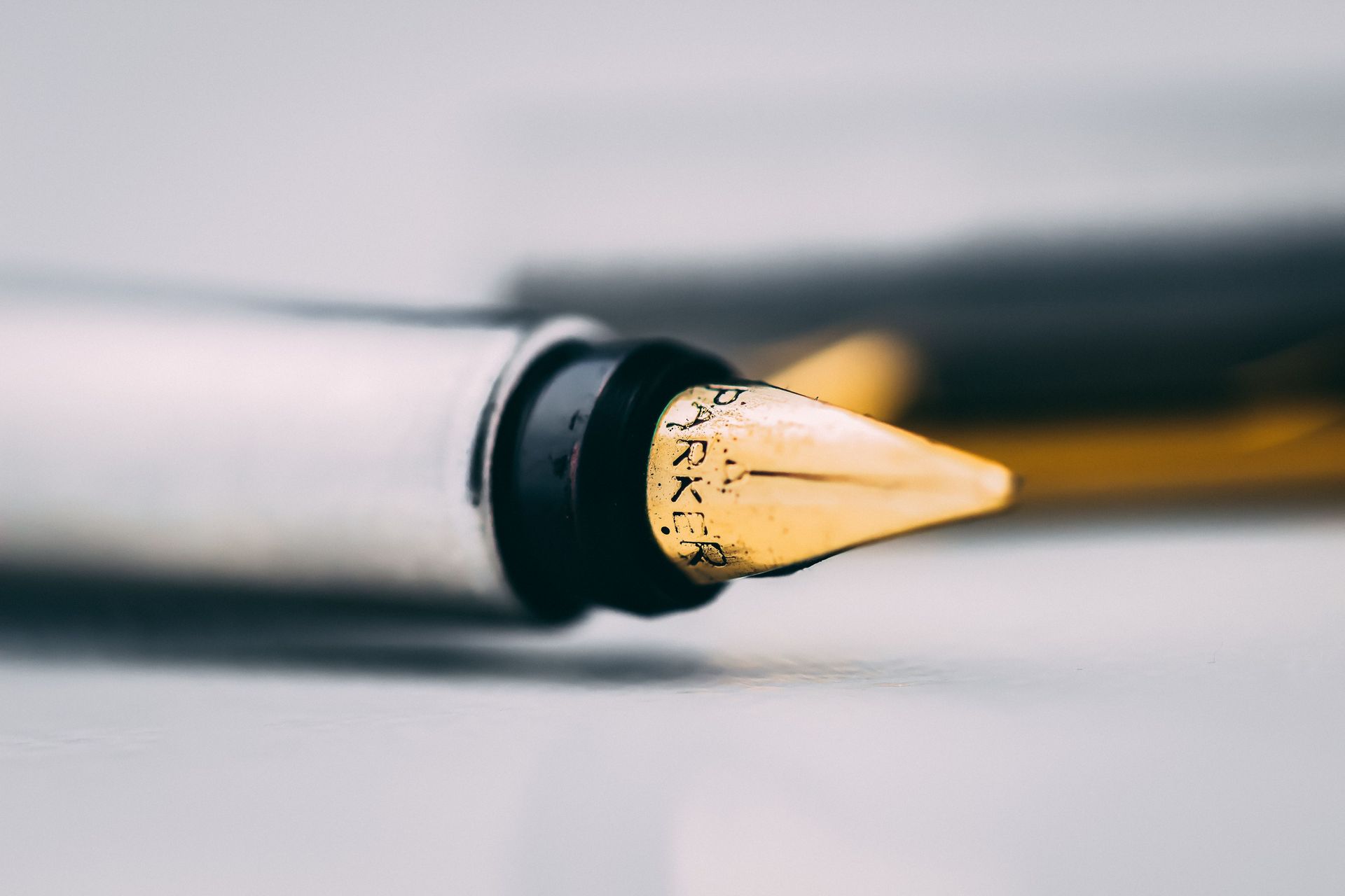 Close-up of a black pen tip with gold ink dots on a white surface