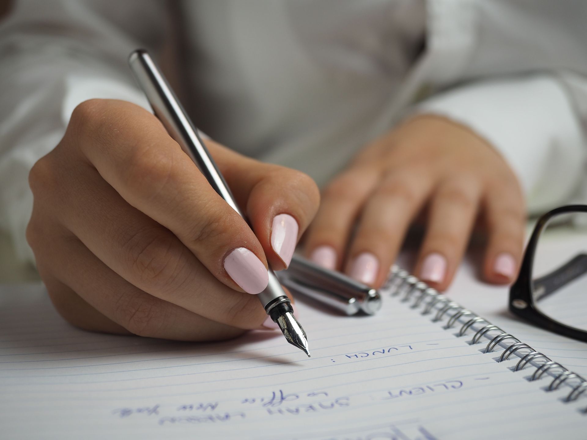 Hand writing notes in a spiral notebook with a pen, close-up on a desk