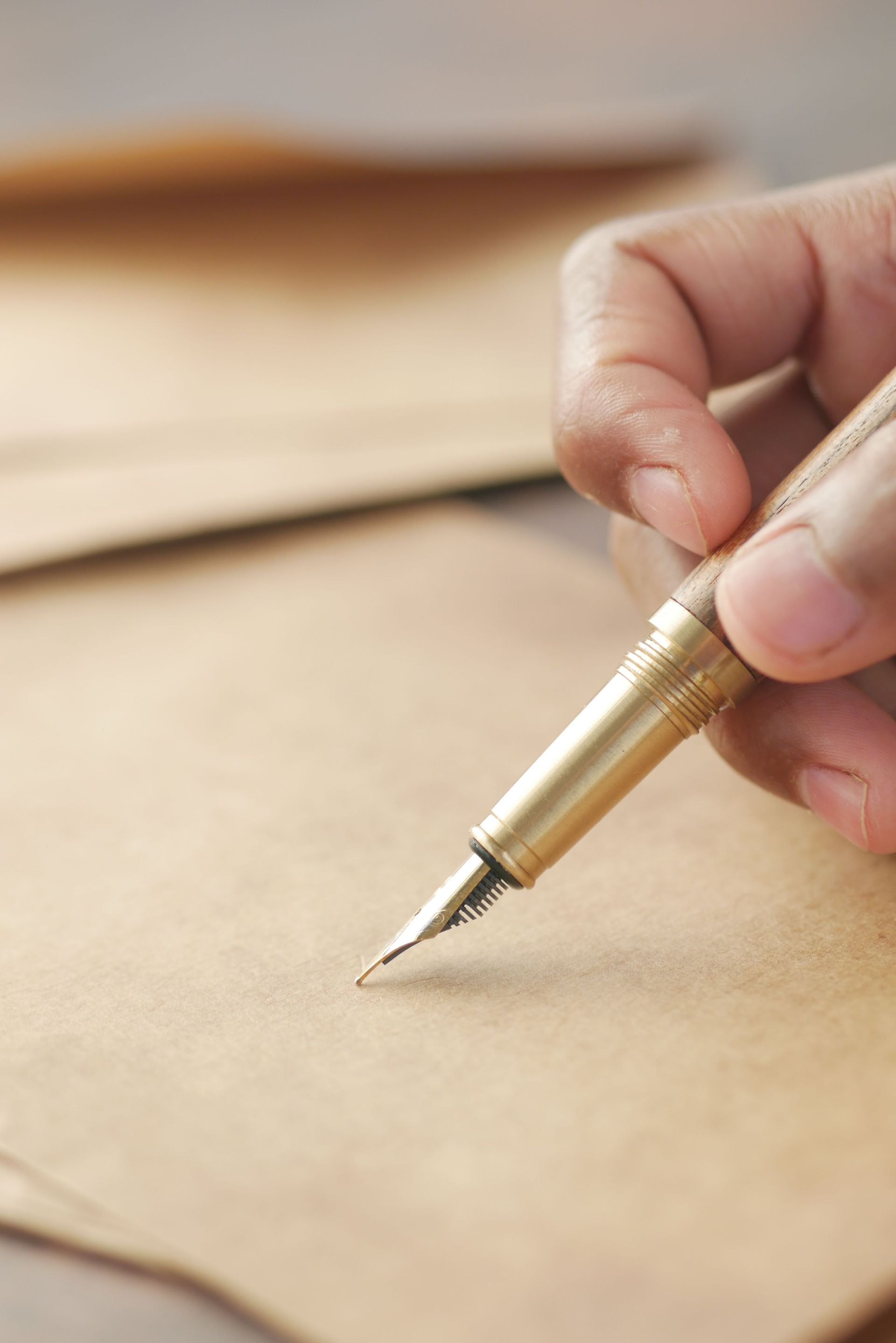 Hand holding a gold fountain pen poised over blank paper