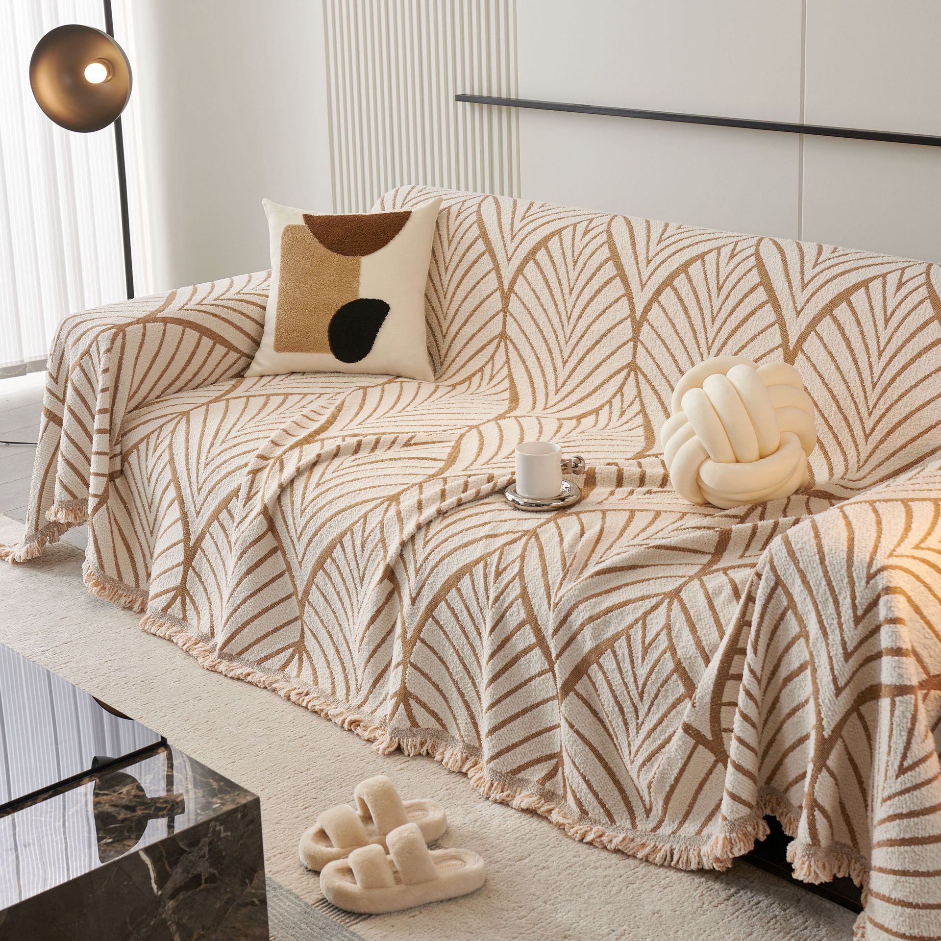 Cream leaf-print sofa with pillows and throws in a cozy minimalist living room