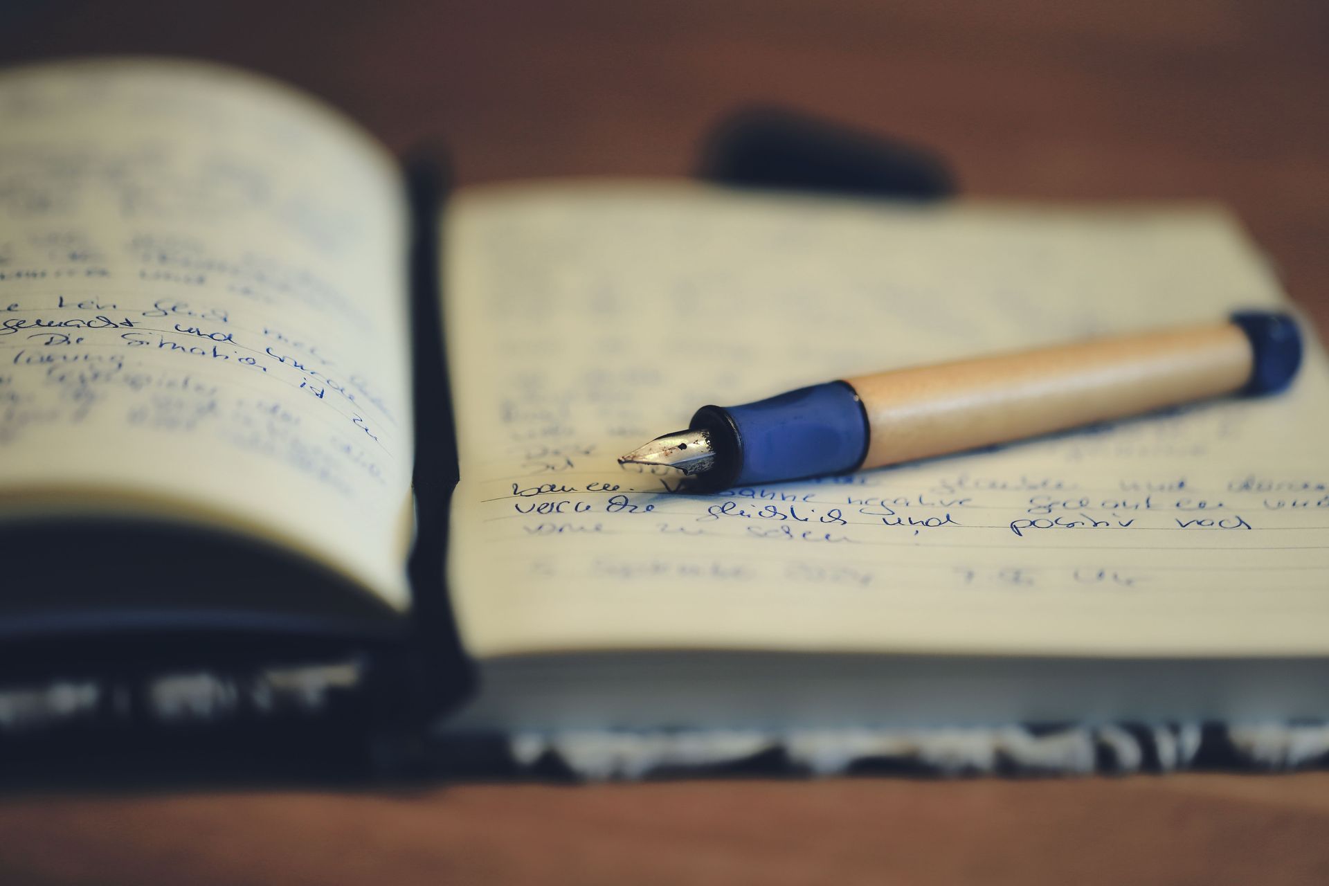 Open book with handwritten notes and a blue pen on a desk