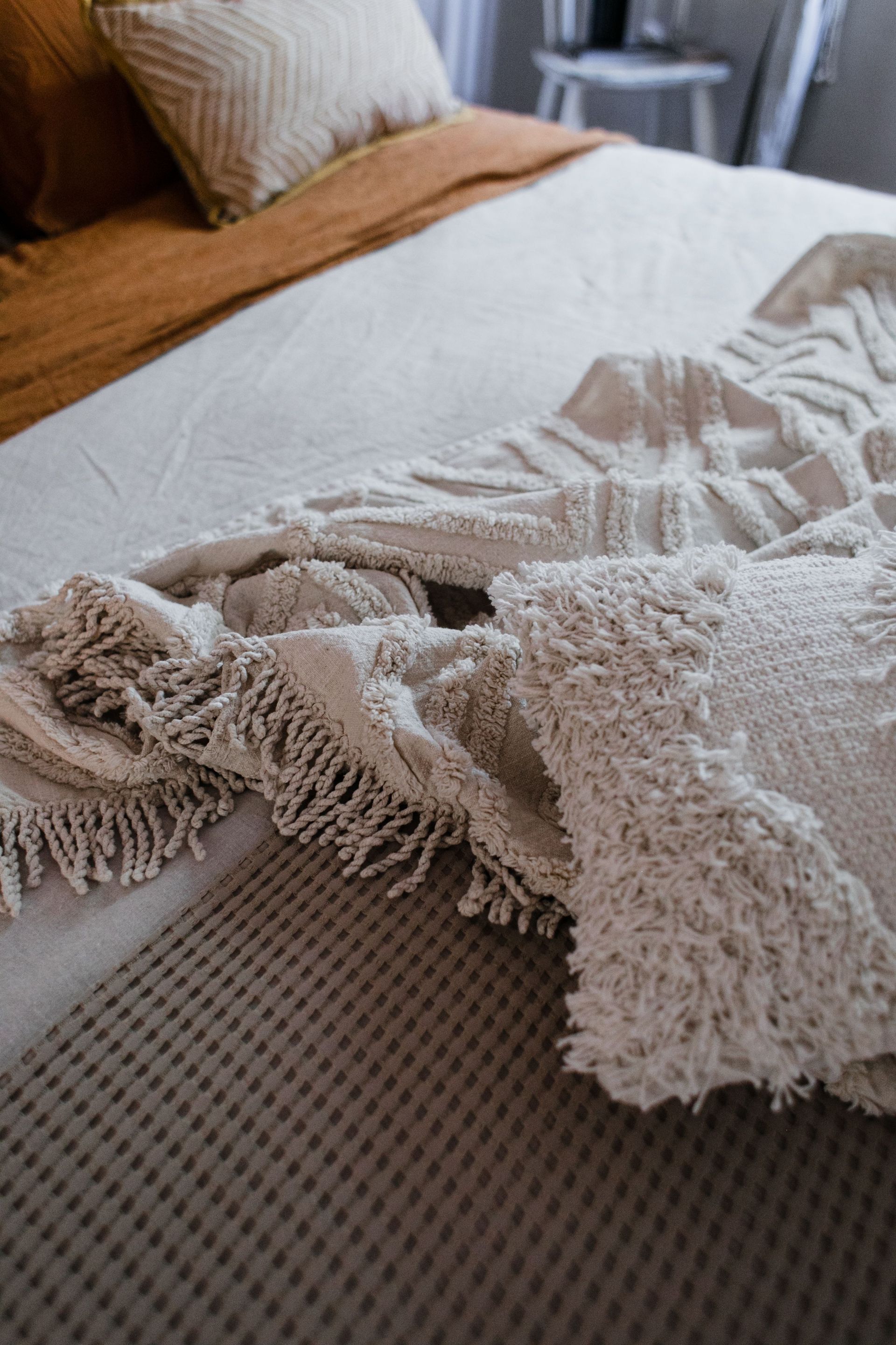 Cozy bed with a beige throw blanket and pillow in a softly lit bedroom