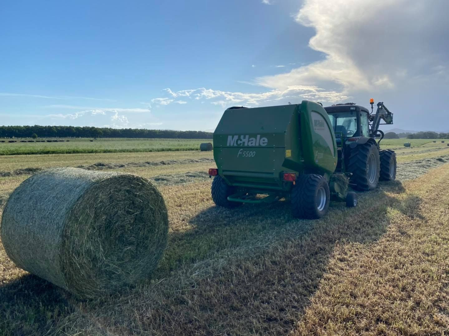 A Red Tractor Is Plowing a Field with A Plow — Thompson's Farm Gear In Wauchope, NSW