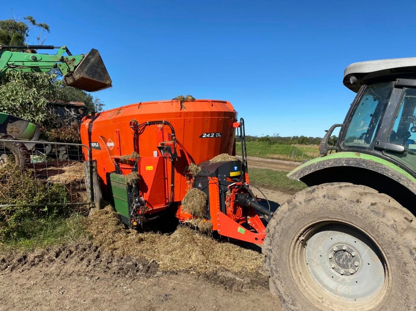A Red Tractor Is Plowing a Field with A Plow — Thompson's Farm Gear In Coffs Harbour, NSW