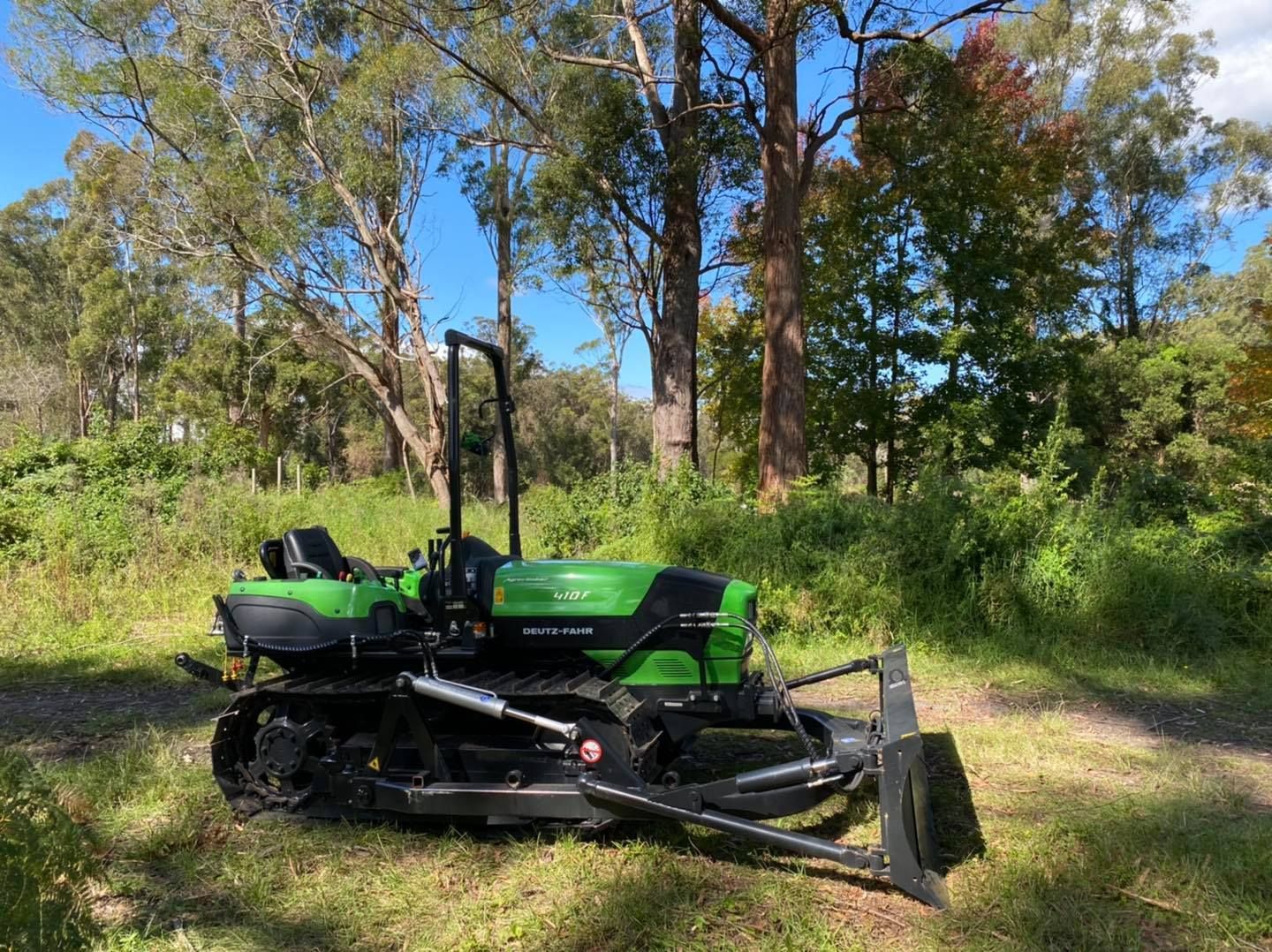 A Red Tractor Is Cutting Grass in A Field — Thompson's Farm Gear In Kempsey, NSW