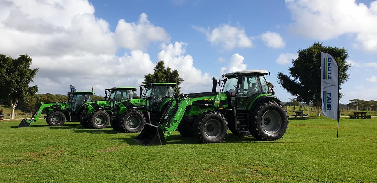 Two Tractors Are Parked in A Grassy Field — Thompson's Farm Gear In Taree, NSW