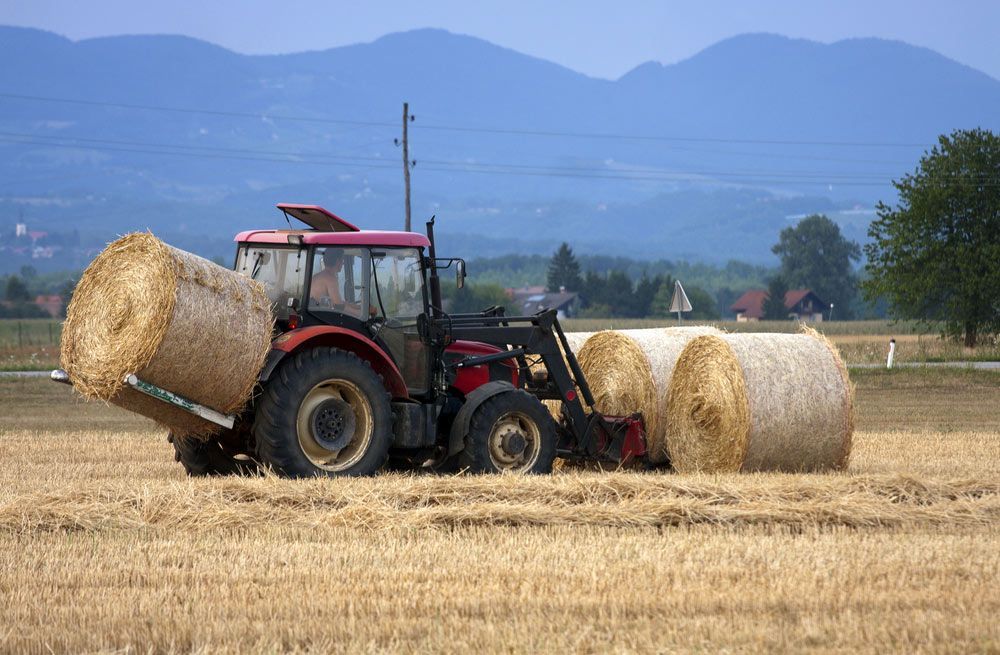 Farmers Maneuvering Hay Bales with Tractor — Thompson's Farm Gear In Wauchope, NSW