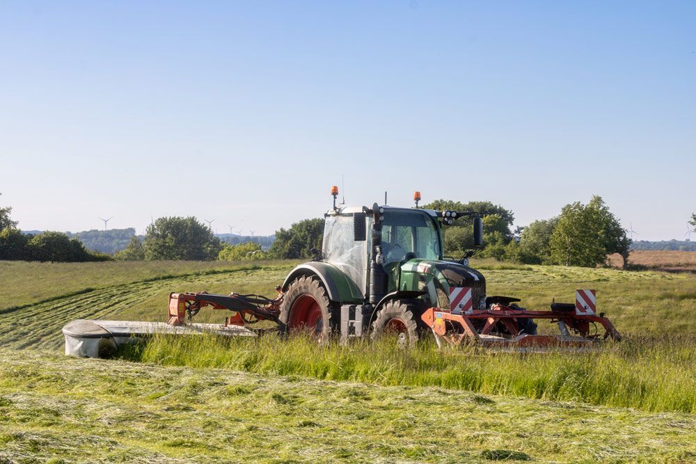 Farmer on Tractor Cutting Grass in the Field — Thompson's Farm Gear In Port Macquarie, NSW
