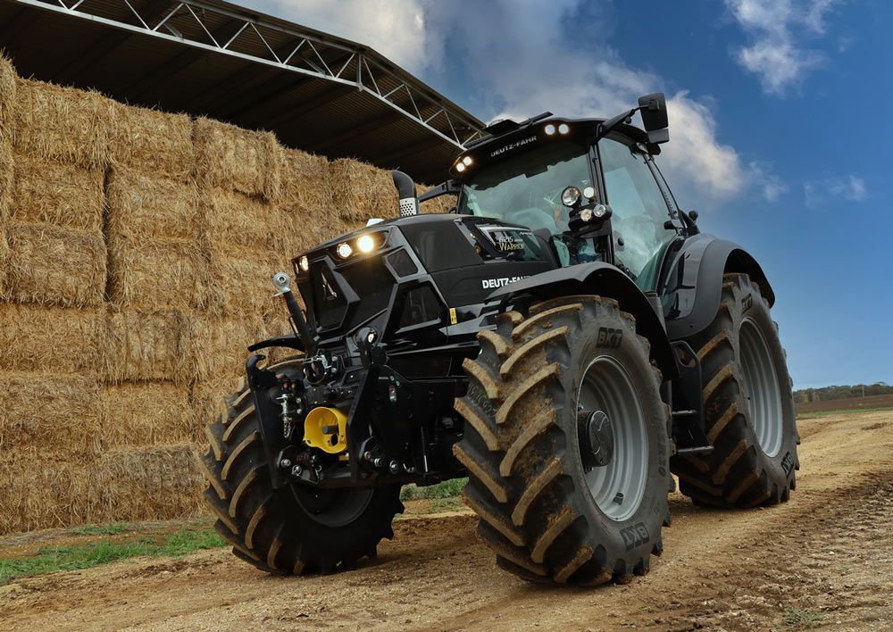 A Black Tractor Is Parked in Front of A Pile of Hay — Thompson's Farm Gear In Wauchope, NSW