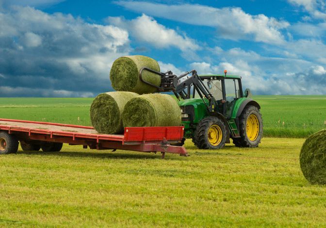 Rural Landscape featuring Tractor and Trailer with Hay Bales — Thompson's Farm Gear In Port Macquarie, NSW