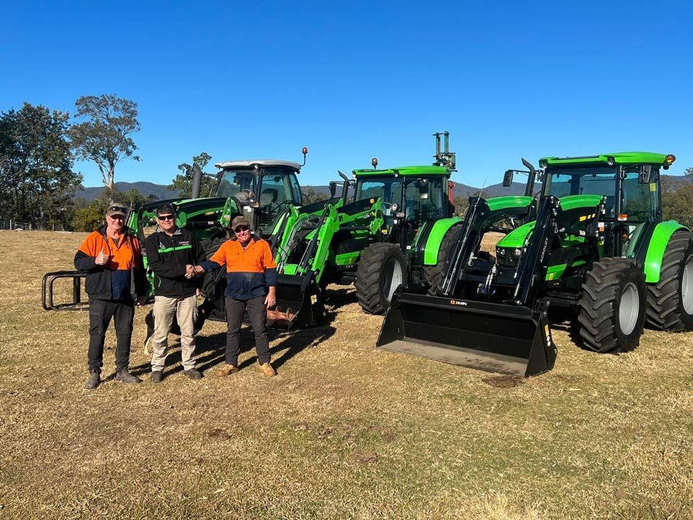 Two Men Shake Hands with Thumbs Up, Tractor in the Background — Thompson's Farm Gear In Wauchope, NSW