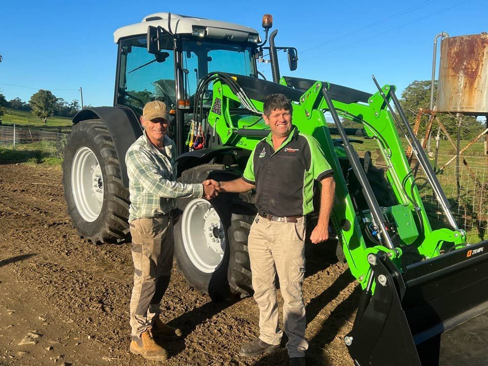 Two Men Shake Hands with Tractor in the Background — Thompson's Farm Gear In Wauchope, NSW