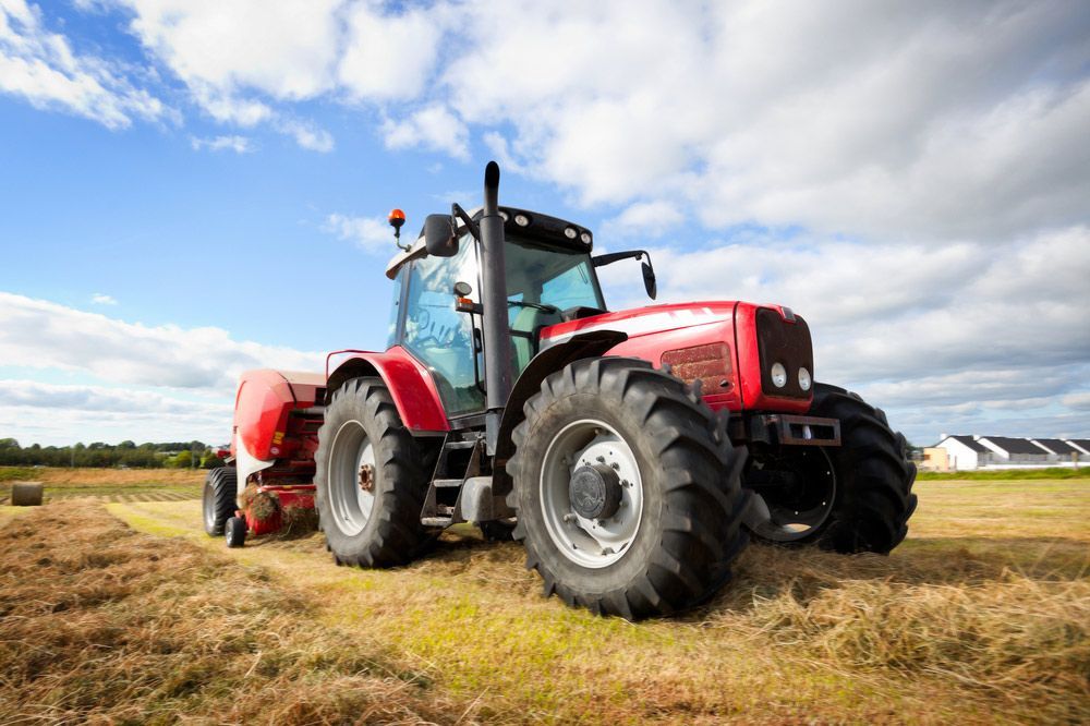 Large Tractor Collecting Hay Bale on the Farm — Thompson's Farm Gear In Kempsey, NSW
