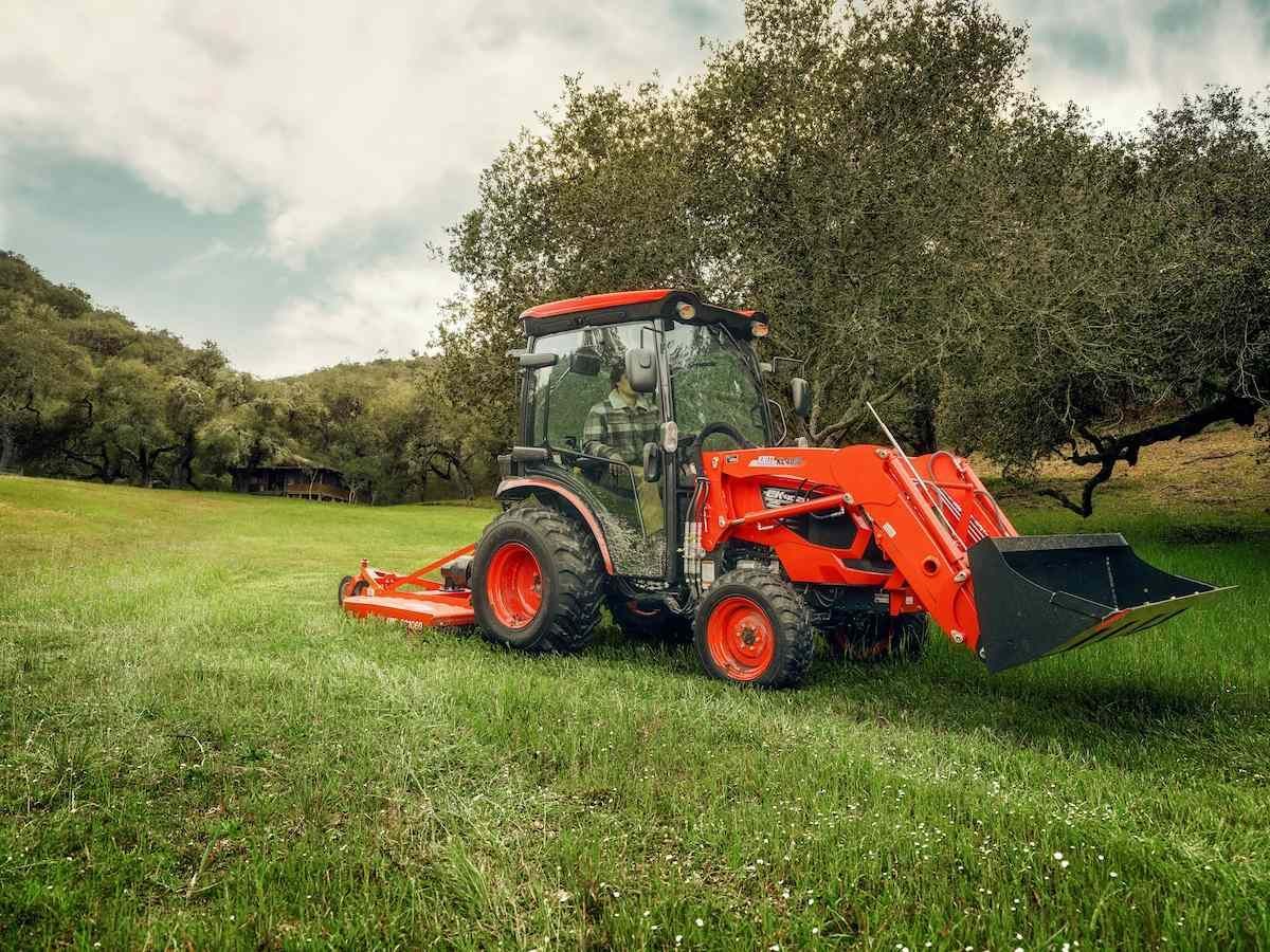 Orange Tractor Mowing Grass In A Green Field Under Cloudy Sky — Thompson's Farm Gear In Port Macquarie, NSW
