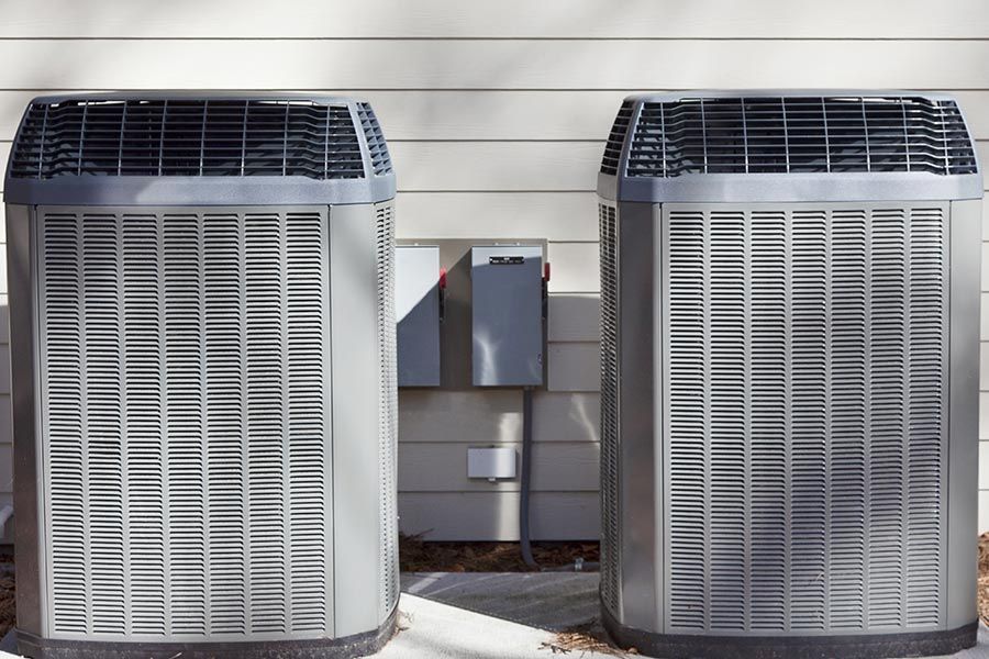 Two outdoor air conditioning units beside a house