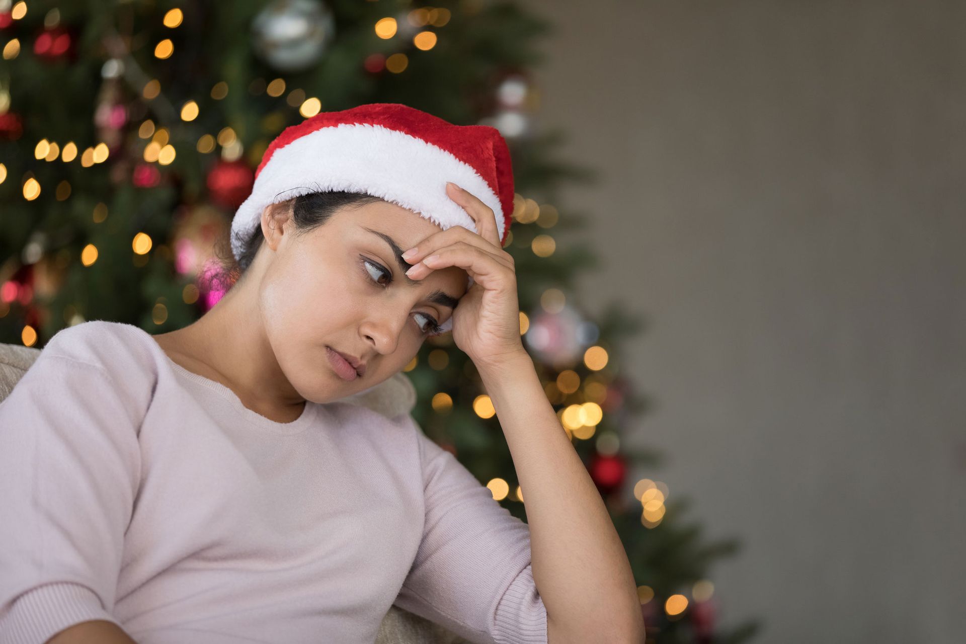 Woman in christmas hat looking sad because she is stressed at work