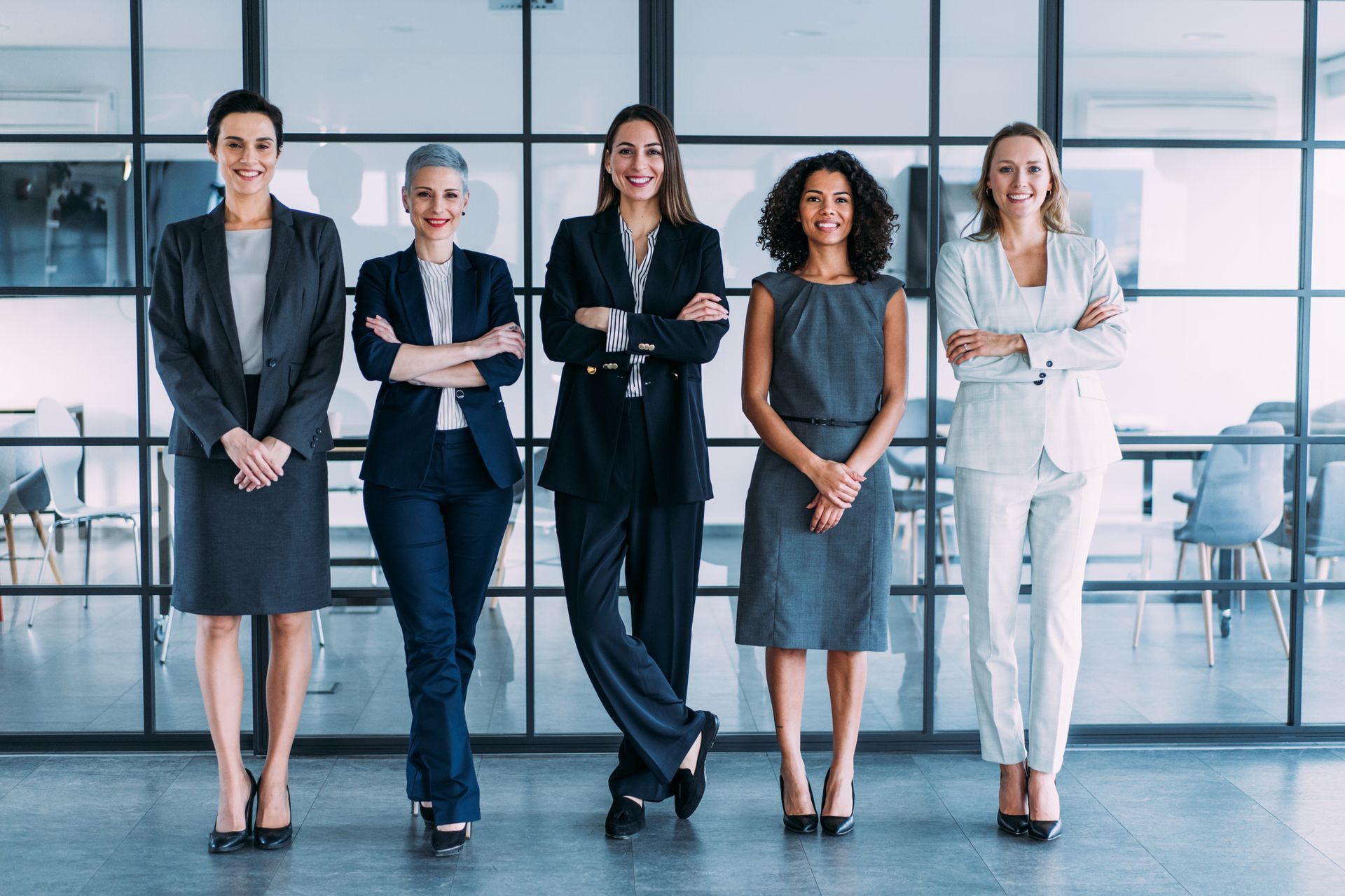 A group of women in business suits are standing next to each other in an office.