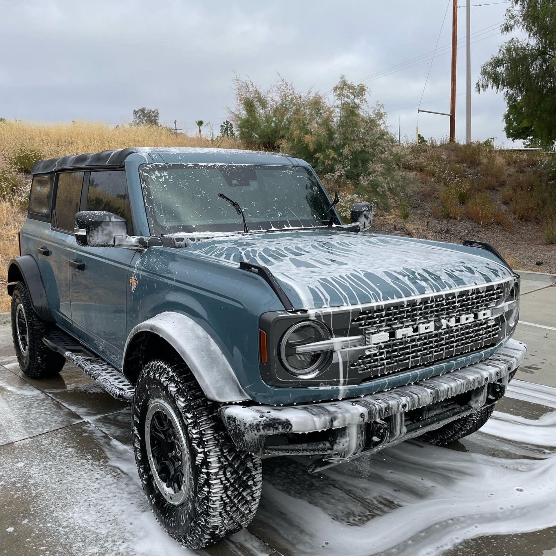 DHD Mobile Car Wash- A blue ford bronco is sitting in a parking lot covered in foam.