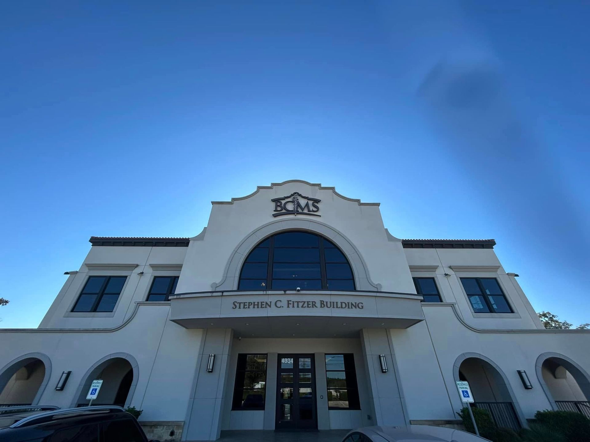 A low-angle view of the light-colored Stephen C. Dyer Building against a bright blue sky.