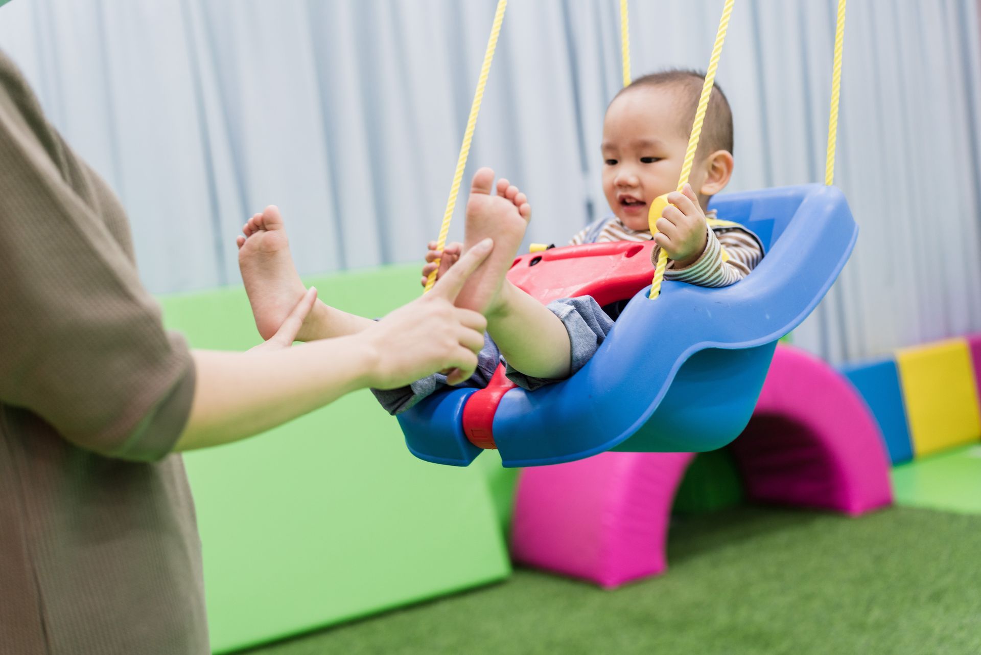 An Asian boy plays with an unrecognized person in a childhood care center.